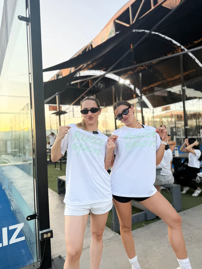 Amigas mostrando sus playeras de Hula en las canchas de pádel